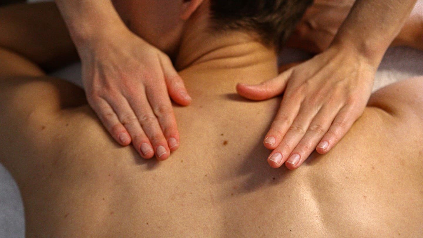 Deux mains à plat travaillant le haut du dos pendant un massage classique
