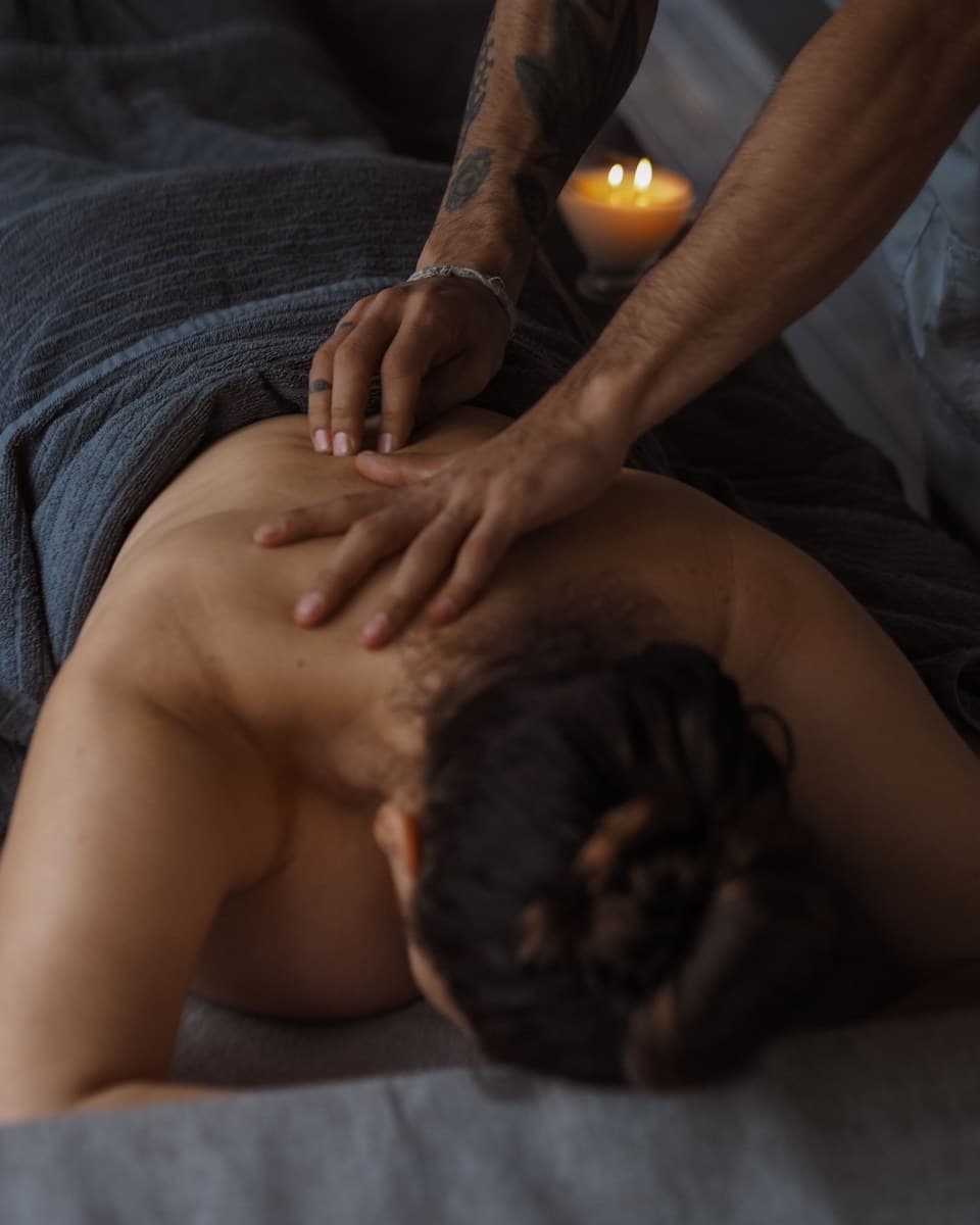 Mains travaillant le haut du dos pendant un massage, à la lumière d'une bougie