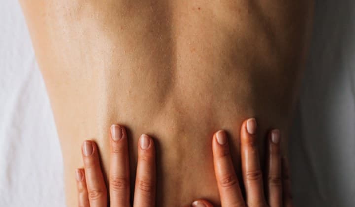 Deux mains posées à plat sur le bas du dos pendant un massage classique