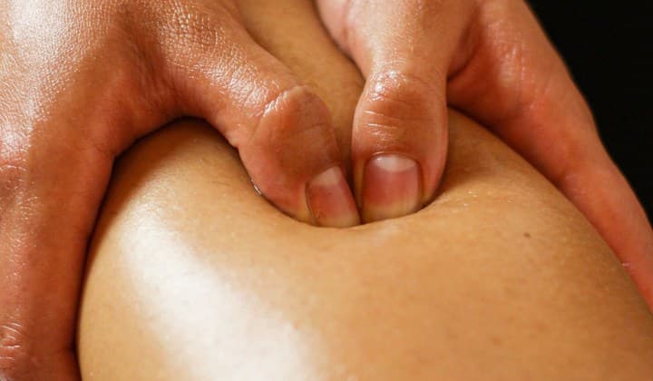 Pouces appuyés sur un mollet lors d'un massage sportif de récupération